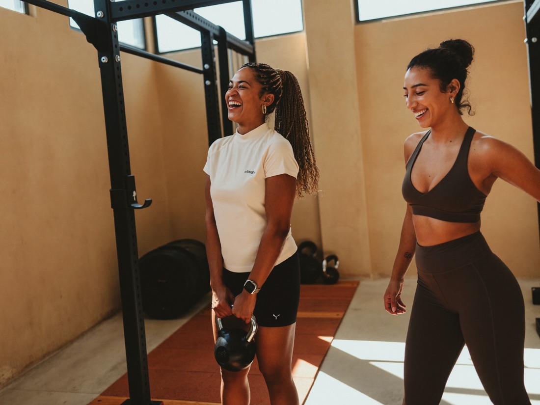 A personal trainer coaching a client in a neighborhood gym
